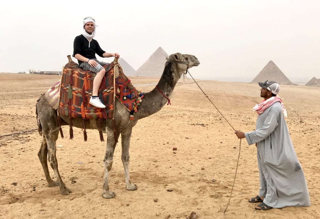 man-sitting-on-camel-in-front-of-the-great-pyramids-of-giza-near-cairo-city-in-egypt_t20_A9lY41-scaled Excursion d’une journée au Caire et aux pyramides de Gizeh au départ d’Hurghada